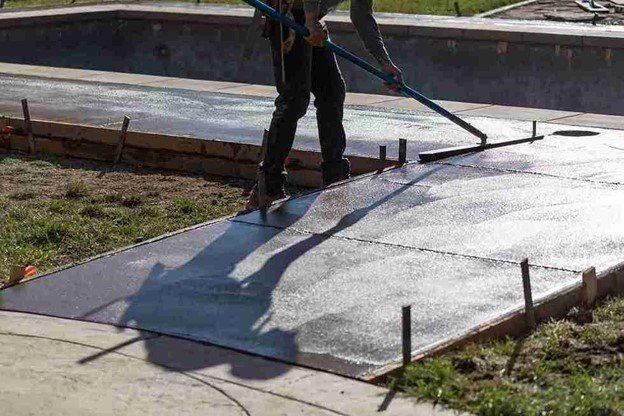 Concrete driveway installation with a worker smoothing freshly poured surface using a finishing tool in Medina, OH