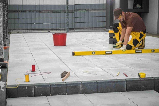 Contractor using a level tool to align large concrete patio slabs during installation in Medina, OH