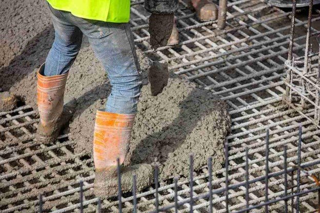 Worker pouring fresh concrete over steel rebar grid for structural slab construction in Medina, OH