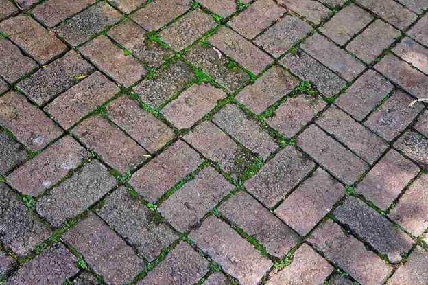 Uneven patio surface with shifting pavers and gaps before concrete patio replacement in Middleburg Heights, OH